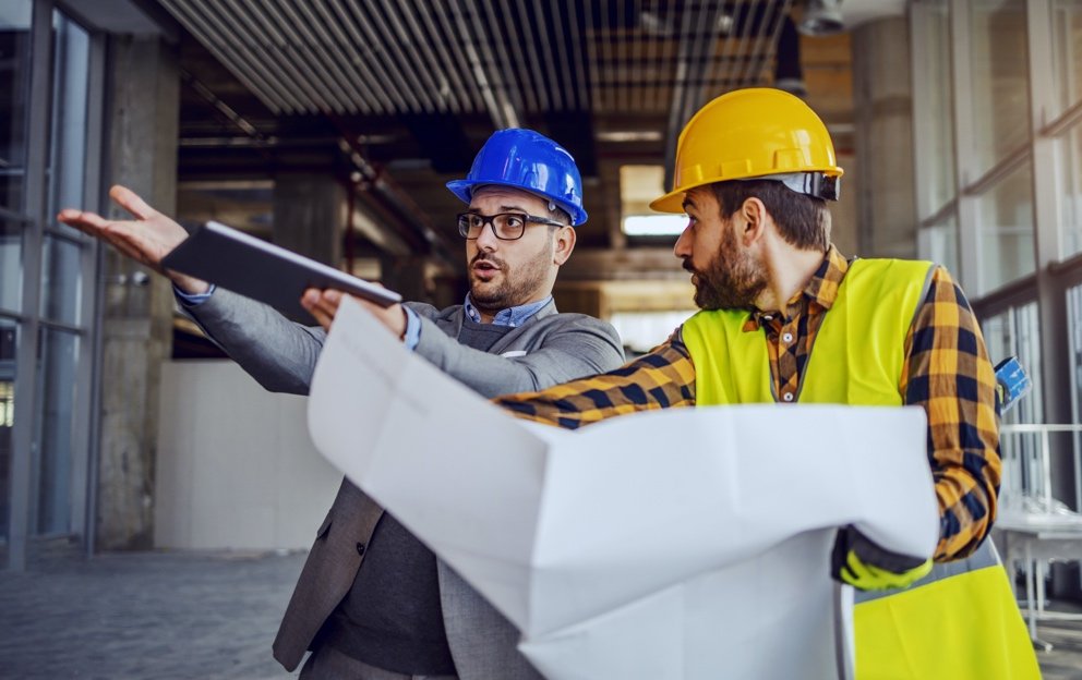 upset-architect-arguing-with-construction-worker-showing-him-his-mistake-worker-holding-blueprints-defending-himself-building-construction-process-interior